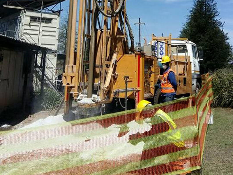drilling truck and individuals behind safety tape