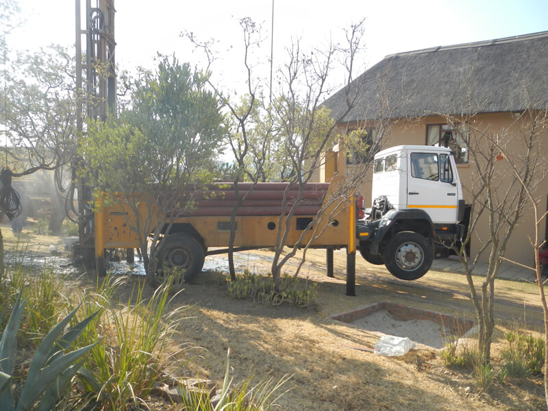 drilling truck next to bush home