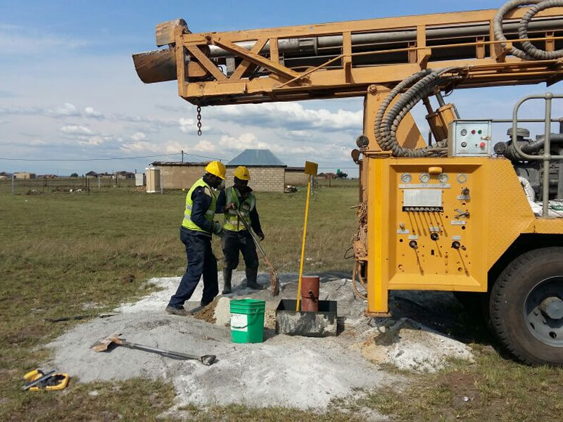 two people wearing safety equipment digging