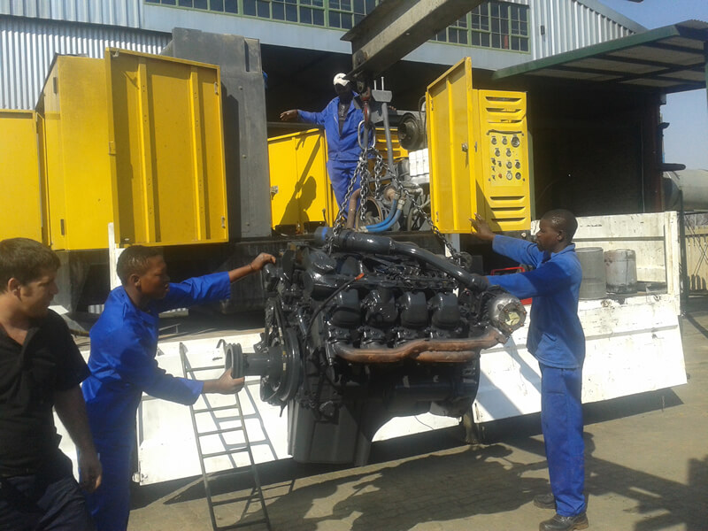 men in overalls moving a large vehicle part