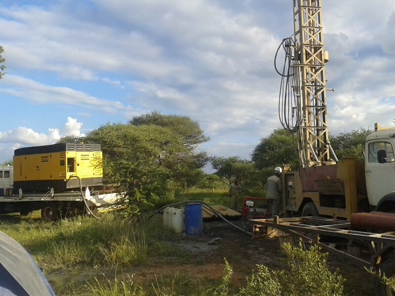 drilling vehicles parked amidst trees with clouds overhead